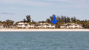 Un hotel sulla spiaggia con edifici a più piani, una spiaggia sabbiosa e un mare calmo.
