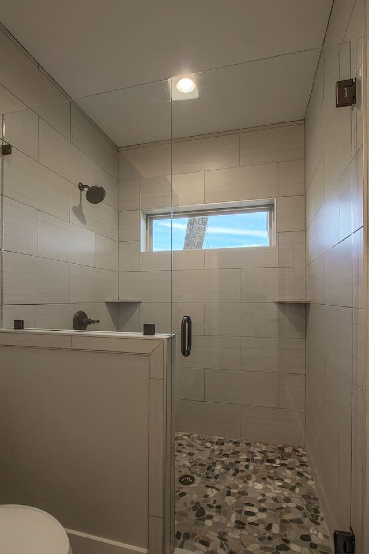 Une salle de bain moderne avec une douche, une fenêtre et un sol carrelé.
