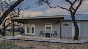 Ein eingeschossiges Haus mit überdachter Terrasse, einer Tür und zwei Fenstern.