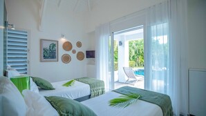 A room with two beds, a TV, and a view of a pool.