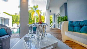 A modern outdoor seating area with a pool, clear glassware, and a bottle of champagne.