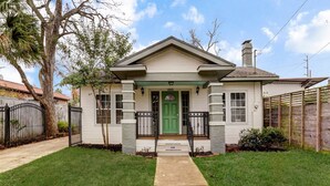 A single-story house with a green front door, a small porch, and a chimney.