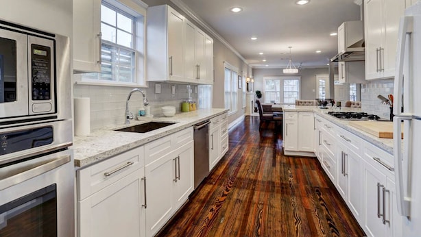 A spacious kitchen with white cabinetry, a central island, and a hardwood floor.