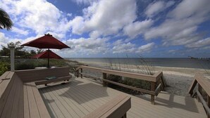 A wooden deck with benches and red umbrellas overlooking a beach. - Direct Gulf View, Beach Condo on Manasota Key, FL (Englewood)