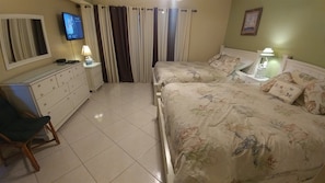 Een slaapkamer met een bed, een televisie, een bureau en een stoel.