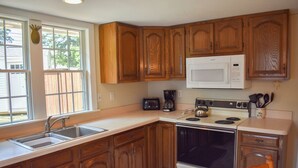 Una cucina con mobili in legno, un forno a microonde, un fornello e un lavandino.