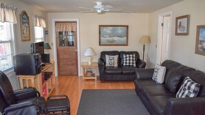 A living room with a sofa, a television, a coffee table, and a door.
