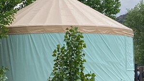 A large, round, tent-like structure with a light blue and beige exterior, surrounded by greenery. - Fantastic and Fun “O Canada" Yurt, sleeps 4 (Rigby)