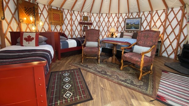 A cozy interior of a yurt with two beds, a dining table, and two chairs. - Fantastic and Fun “O Canada" Yurt, sleeps 4 (Rigby)