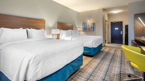 A hotel room with two beds, a desk, a chair, a lamp, and a painting on the wall.