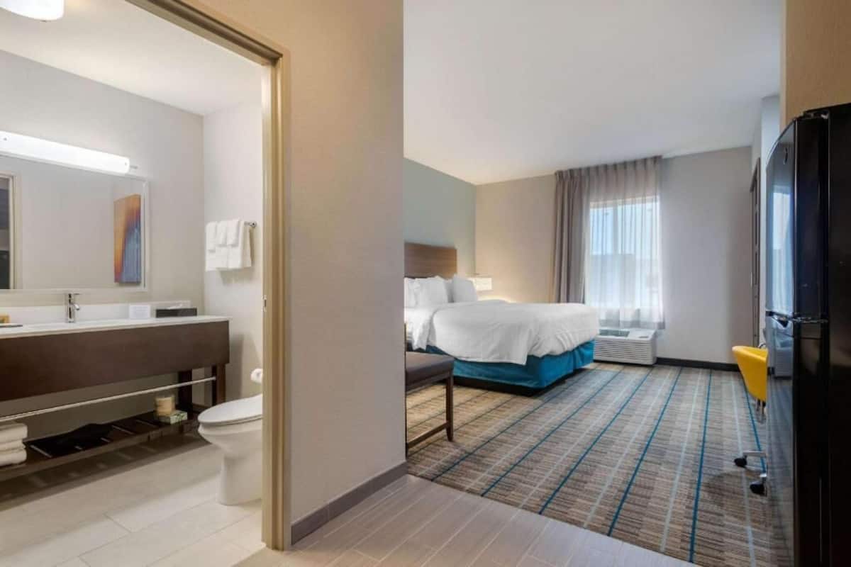 Een hotelkamer met een badkamer, een bed, een bureau en een stoel.