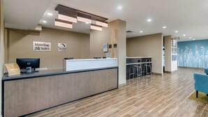 A hotel reception area with a modern design, including a reception desk, a computer, and a seating area with bar stools.