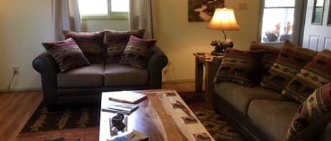 A living room with two sofas, a coffee table, and patterned rugs.