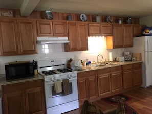 Una cocina con armarios de madera, estufa blanca, microondas y refrigerador.