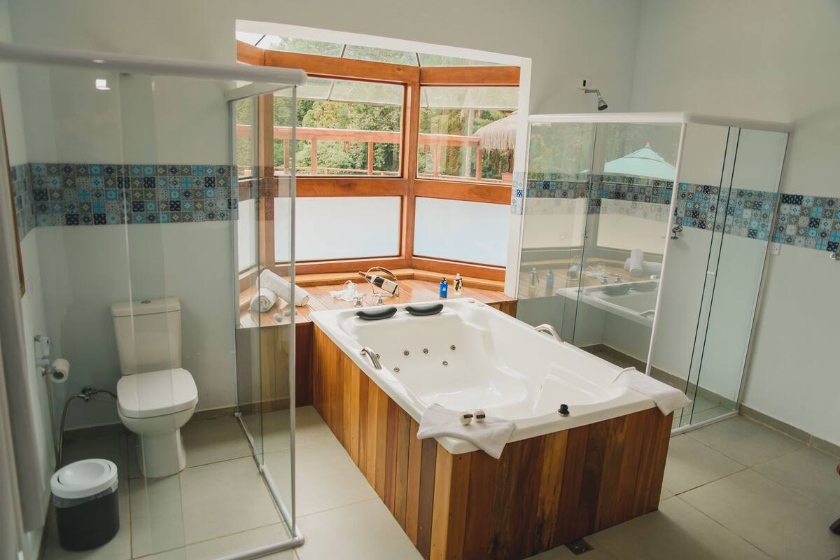 A modern bathroom with a glass-enclosed shower, a large wooden bathtub, and a toilet.