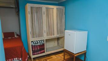 A bedroom with a bed, a wardrobe, and a refrigerator.