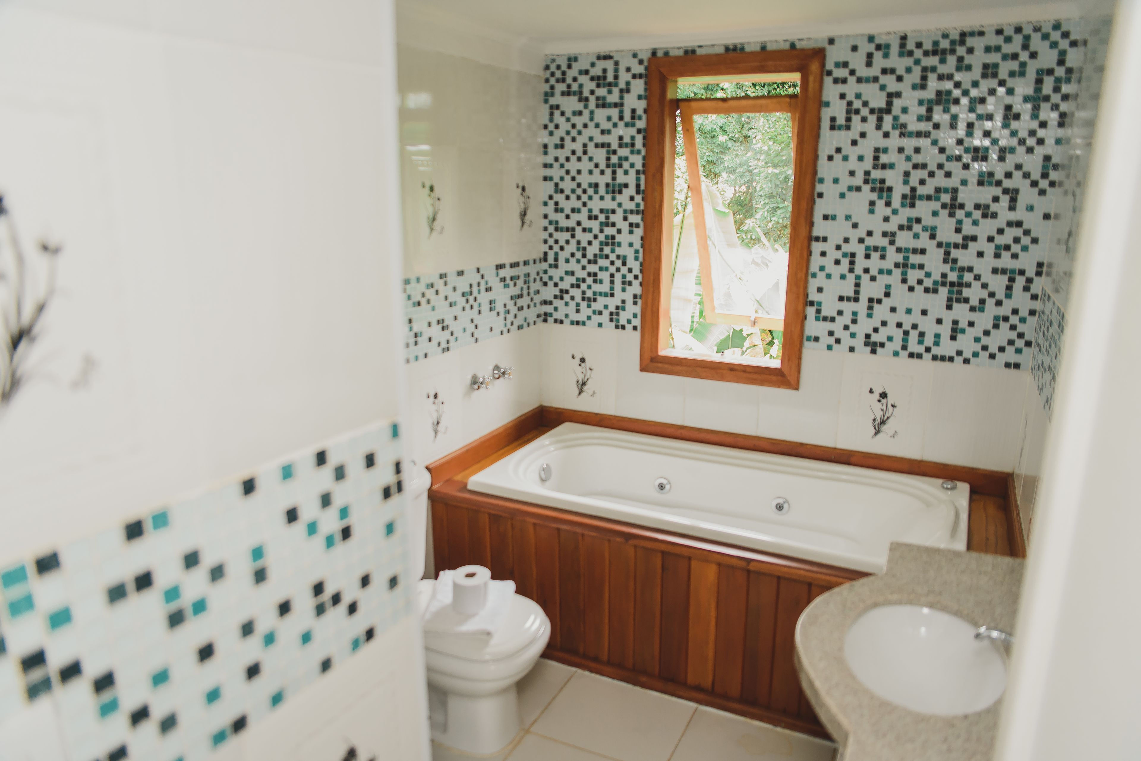 A bathroom with a wooden bathtub, a toilet, and a sink.