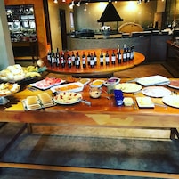 Buffet com diversos tipos de comida e seleção de garrafas de vinho.