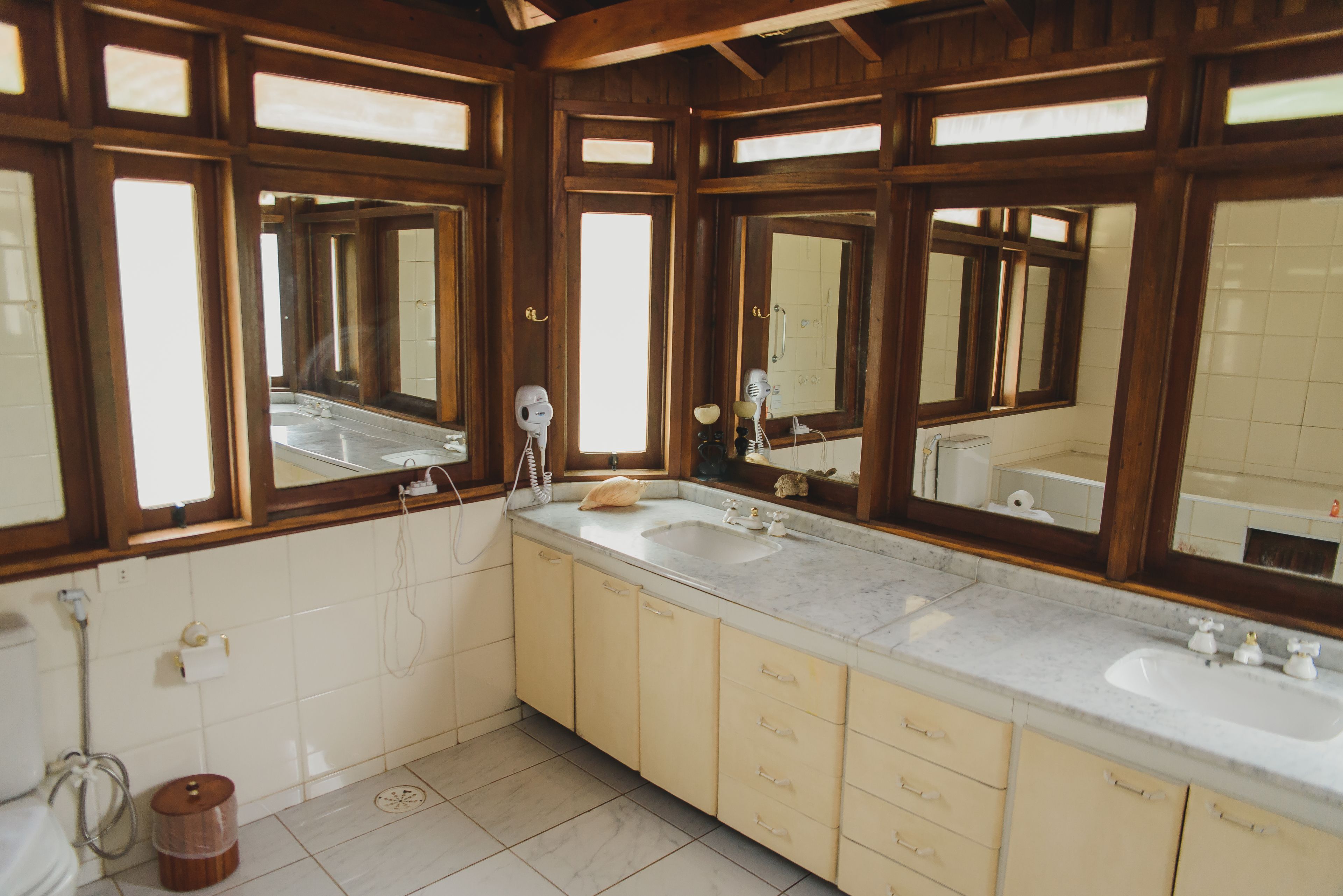 Un baño con dos lavamanos, armarios de madera y espejos grandes.