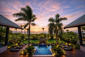 A pool area with lounge chairs, palm trees, and a sunset view. - Naisoso Island Villas (Nadi)