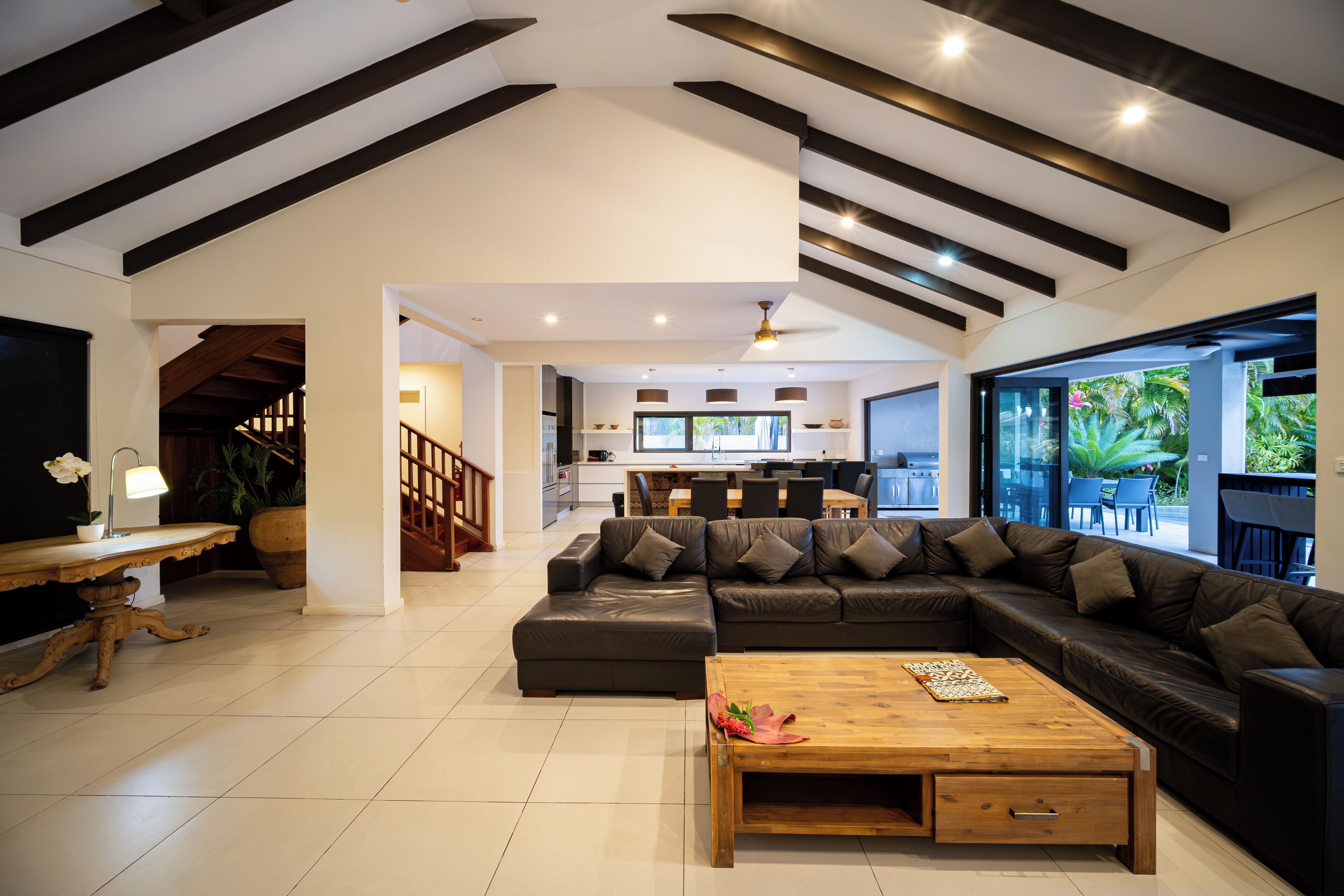 A spacious living area with a large sectional sofa, a wooden coffee table, and a kitchen in the background.