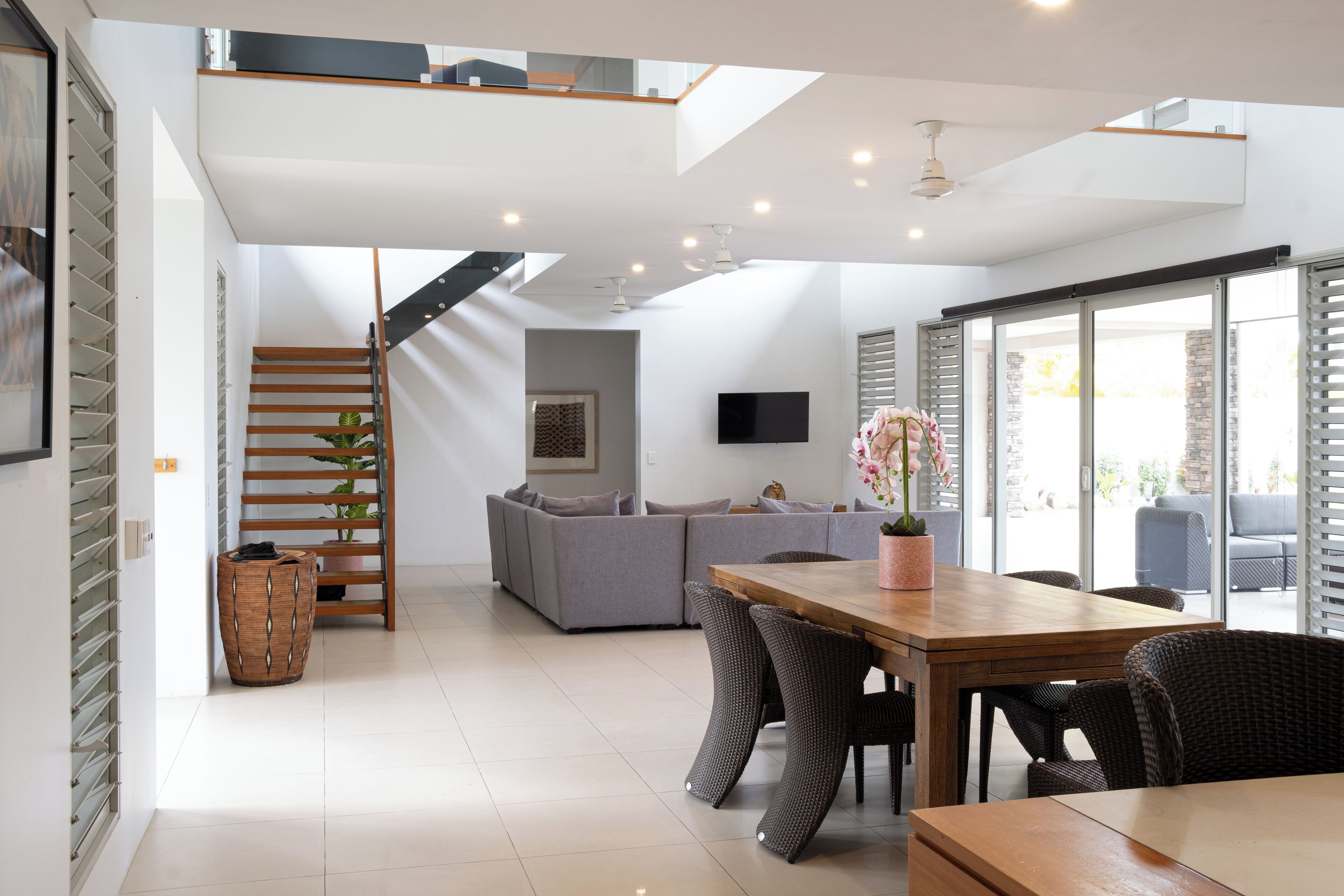 A modern living space with a dining area, a staircase, and a sofa.