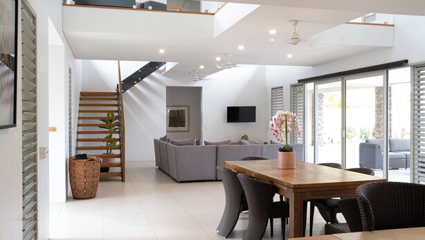 Ein zeitgemäßer Wohnraum mit Essbereich, Treppe und Sofa.