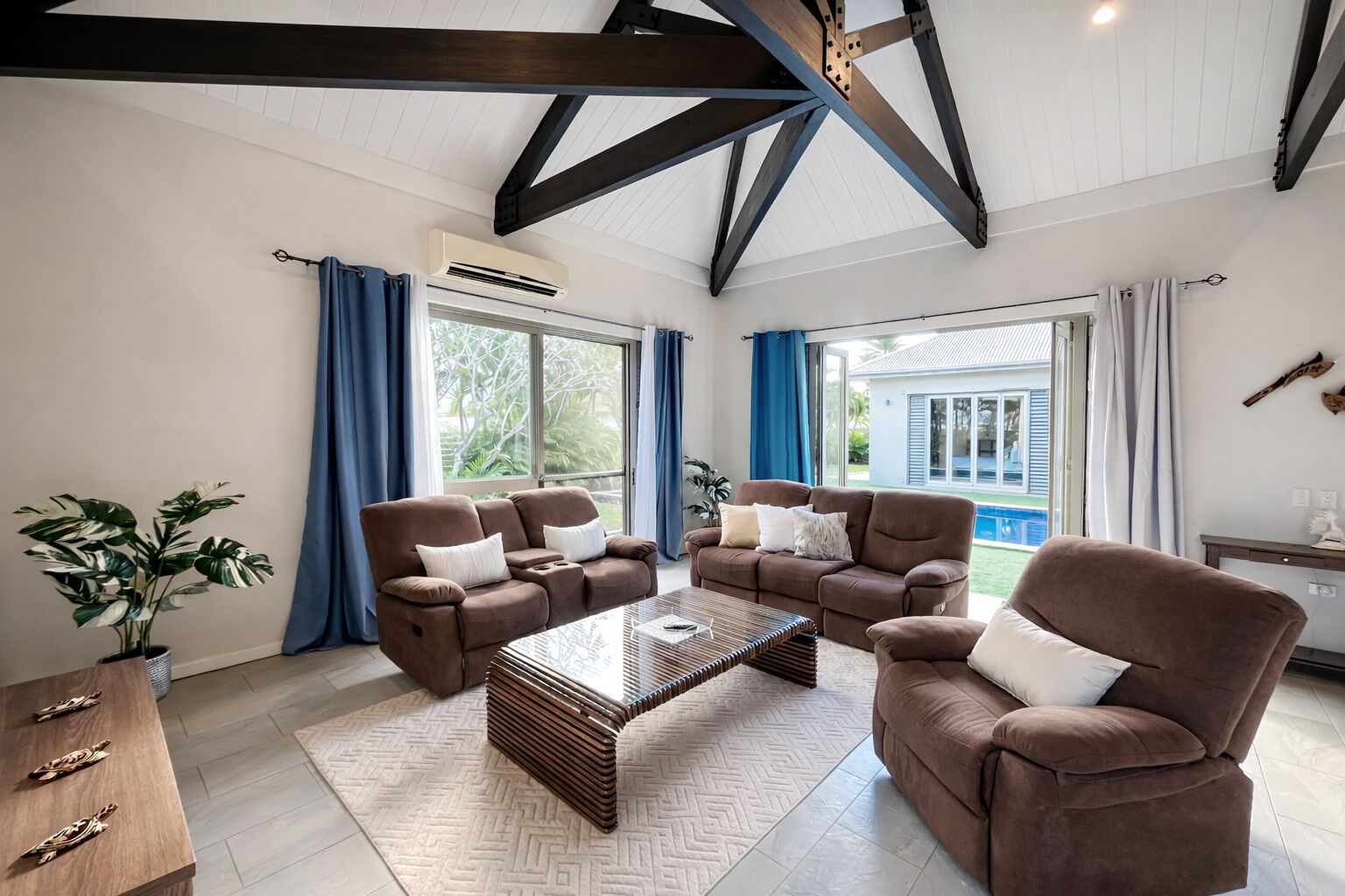 A spacious living room with two brown sofas, a coffee table, and a wooden side table.