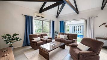 A spacious living room with two brown sofas, a coffee table, and a wooden side table.