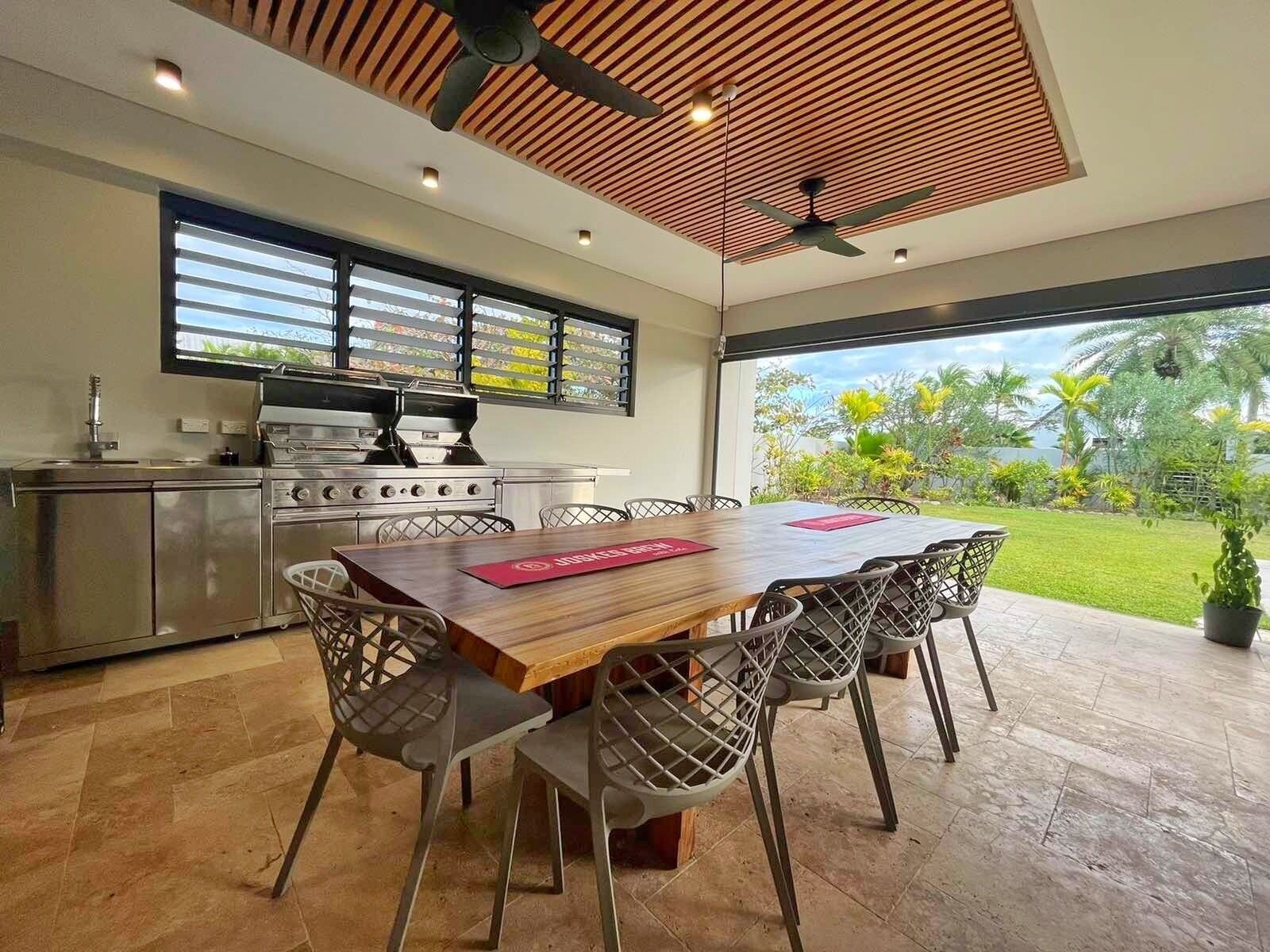 A modern kitchen with a gas stove, a built-in oven, and a large window overlooking a garden.