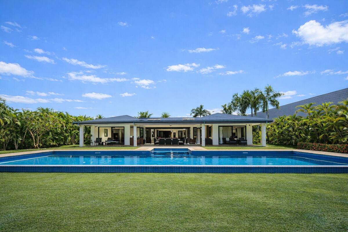 Ein modernes Haus mit Swimmingpool, überdachter Terrasse und üppiger Bepflanzung.