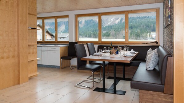 A modern kitchen with a dining area, large windows with mountain views, and a cozy seating arrangement.