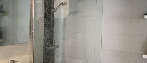 A modern bathroom with a glass shower enclosure, a white sink, and a mirror.