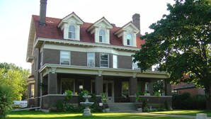 A two-story brick house with a front porch, a large lawn, and a chimney. - 9 Bedroom Historic Summit Mansion With Pool And Hot Tub (St Paul)