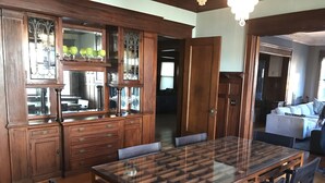 A dining area with a wooden table and chairs, a kitchen with wooden cabinets and a glass-fronted island, and a living room with a sofa and a TV. - 9 Bedroom Historic Summit Mansion With Pool And Hot Tub (St Paul)