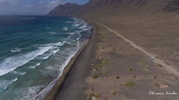 Una carretera costera con una playa y acantilados rocosos.