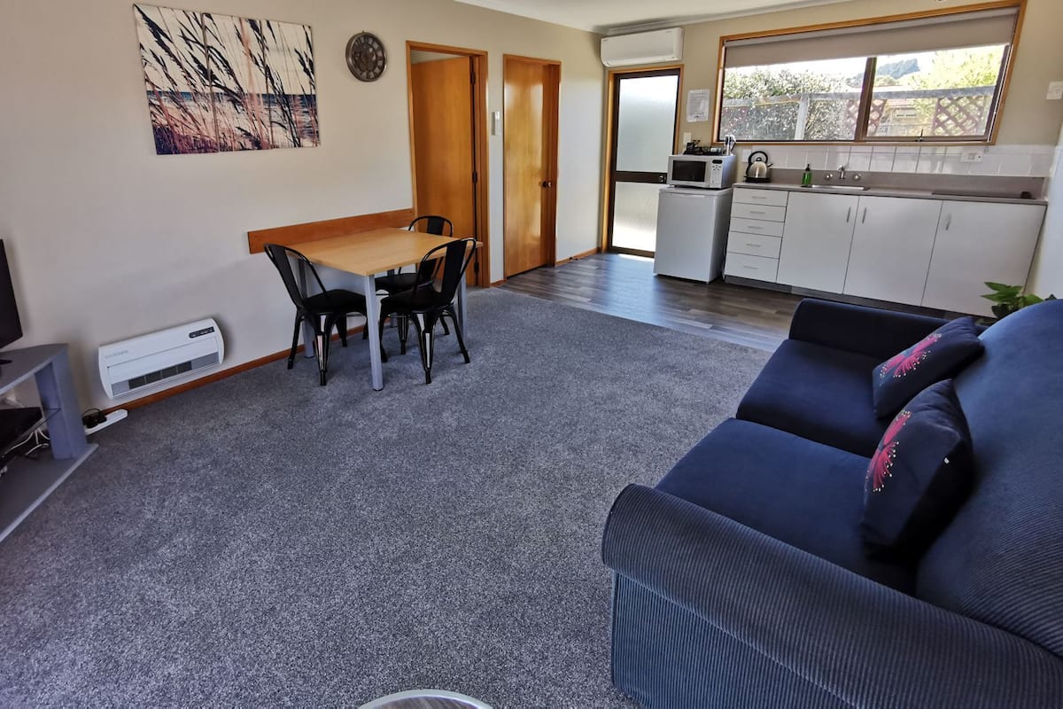 Un espacio habitable compacto con comedor, kitchenette y zona de estar.