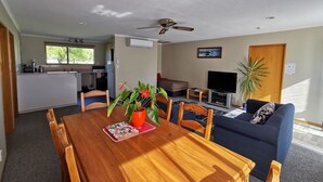 A compact living space with a dining area, kitchenette, and a seating area with a TV. - Broadview Motel (Cheviot)