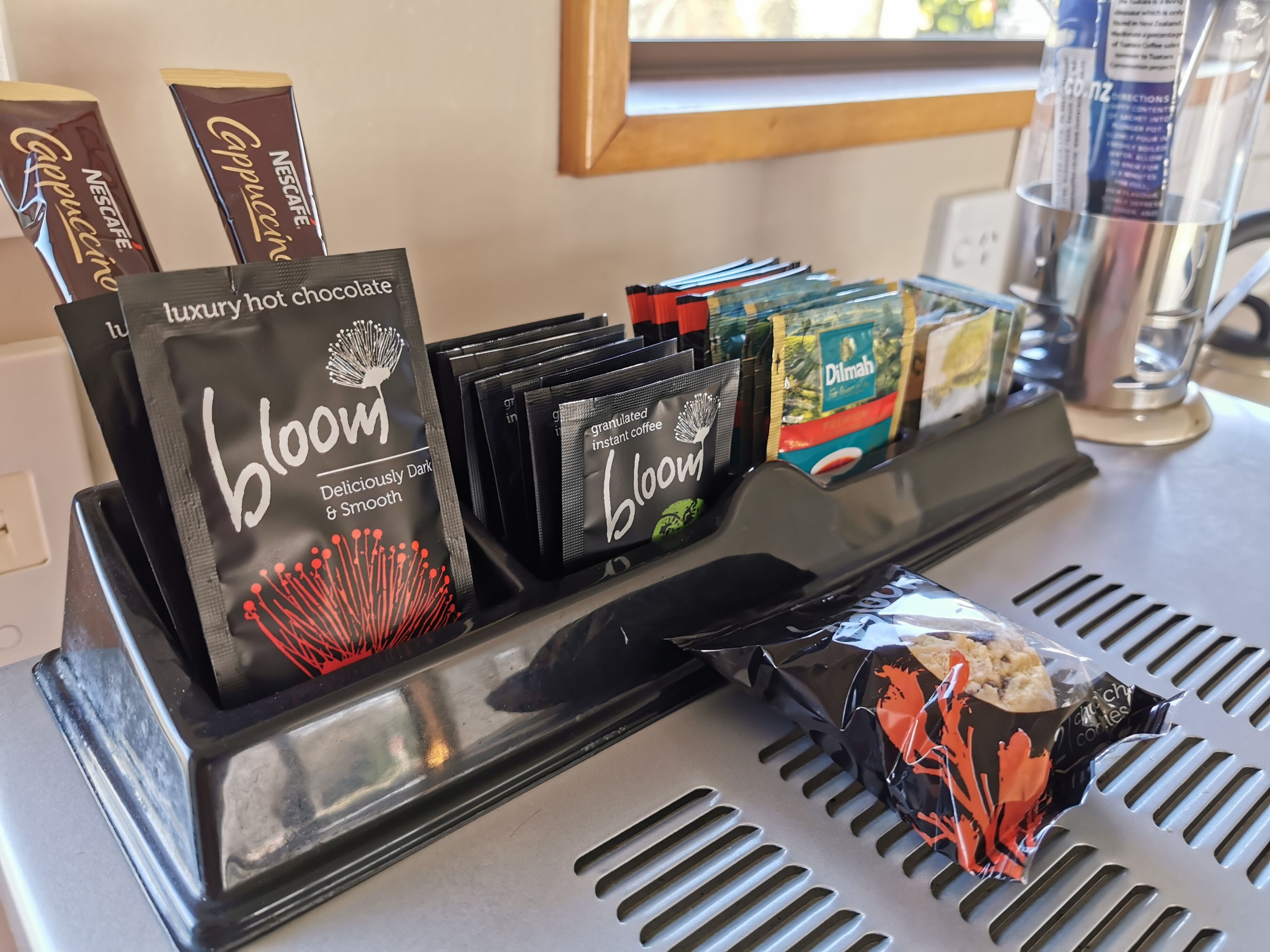 A coffee station with branded coffee packets, instant coffee packets, and a packaged snack.