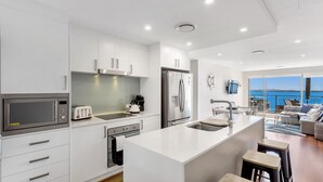 Une cuisine moderne avec des meubles blancs, des appareils en acier inoxydable et un grand îlot central.