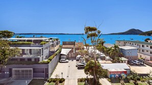 Une zone résidentielle côtière avec des bâtiments modernes, une marina remplie de bateaux et un ciel bleu dégagé.