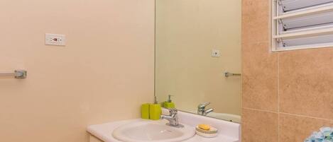 A bathroom with a sink, mirror, and towel rack.
