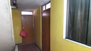 A narrow hallway with yellow walls, a red bag hanging on the left, and a window on the right. - Third floor apartment (Ayacucho)