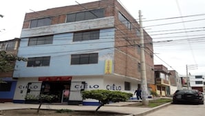 A two-story building with a blue and white facade, a small garden area, and a visible entrance. - Third floor apartment (Ayacucho)