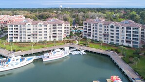 A marina with a large boat docked, surrounded by multi-story buildings with balconies and a well-maintained landscape.