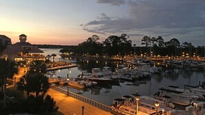 A marina at dusk with boats docked, a waterfront restaurant, and a gazebo.
