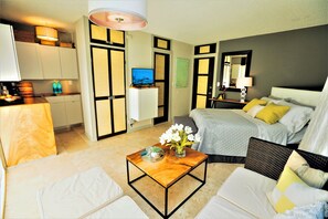 Ein Hotelzimmer mit einem Bett, einer Couch, einem Couchtisch, einem Fernseher und einer Küchenzeile.