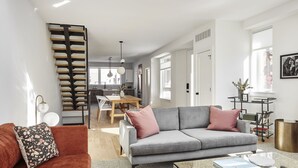 A modern living room with a grey sofa, a red couch, and a glass coffee table. - Absolute Luxury! Sleeps 16! RoofDeck/Gym/Wet Bar (Philadelphia)