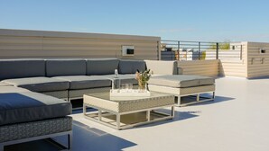 A rooftop terrace with a sectional sofa, a coffee table, and a small table with a vase. - Absolute Luxury! Sleeps 16! RoofDeck/Gym/Wet Bar (Philadelphia)