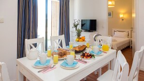 Una mesa con sillas y un televisor al fondo, dispuesta para el desayuno.